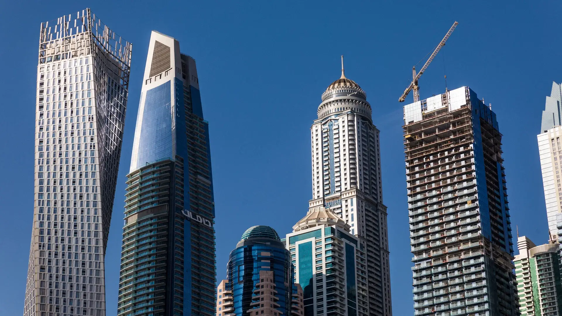 A skyline view of Dubai featuring iconic skyscrapers and ongoing construction, representing the city's dynamic real estate market.