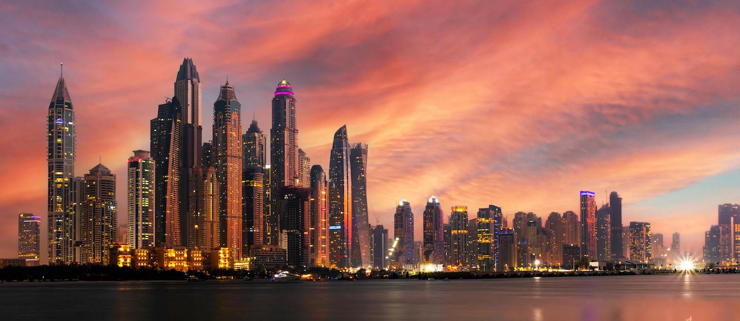 Scenic view of Dubai Marina at sunset, with modern skyscrapers reflecting on the water.