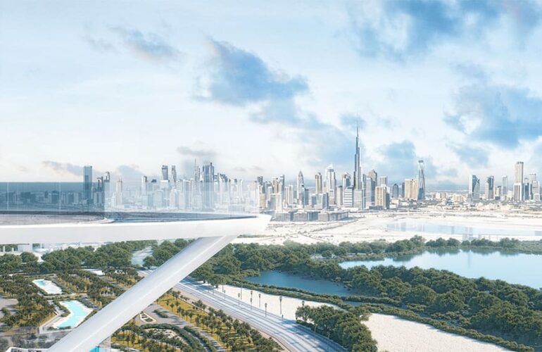 The image appears to showcase a futuristic cityscape with a skyline featuring numerous skyscrapers, including a prominent tall tower that resembles the Burj Khalifa. The foreground includes a modern architectural structure with a sleek, white design, possibly an observation deck or a bridge. Below, there are lush green areas, water bodies, and a network of roads. The sky is mostly clear with some scattered clouds, giving the scene a bright and airy atmosphere.