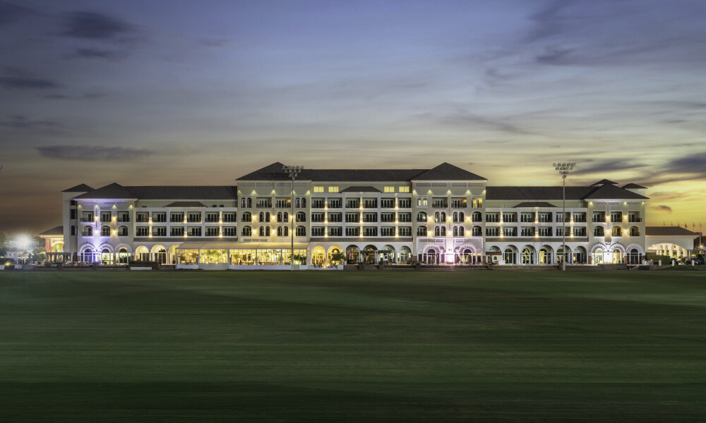 A luxurious hotel building at dusk with elegant lighting, part of Al Habtoor Polo Resort & Club Dubai.