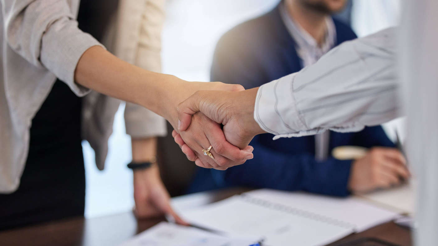 A conceptual image, such as the handing over of keys, a handshake sealing a contract, or someone examining a scale model of a construction project.
