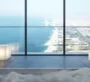 Inside a bathroom where a woman is in a bathtub with a view to the beach