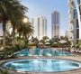 Photo of a jacuzzi and a swimming pool side by side, where there are two people in the pool, and there are two palm trees next to the pool.