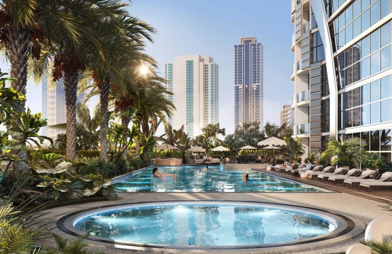 Photo of a jacuzzi and a swimming pool side by side, where there are two people in the pool, and there are two palm trees next to the pool.