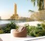 Scenic balcony lounge with view of Dubai Creek Tower surrounded by lush greenery.
