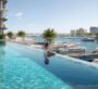 Woman relaxing in an infinity pool at Baystar by Vida in Dubai, with palm trees and yachts in the background.