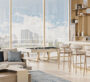 Modern open-plan living and kitchen space in Cove Edition 6, Dubai, filled with natural light through floor-to-ceiling windows.