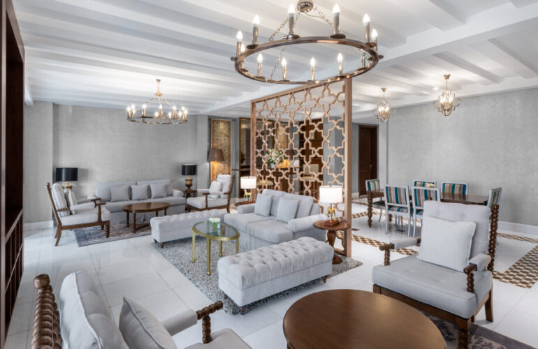 A spacious and beautifully designed living room in a luxury villa at Al Habtoor Polo Resort & Club Dubai, featuring chandeliers and classic decor.