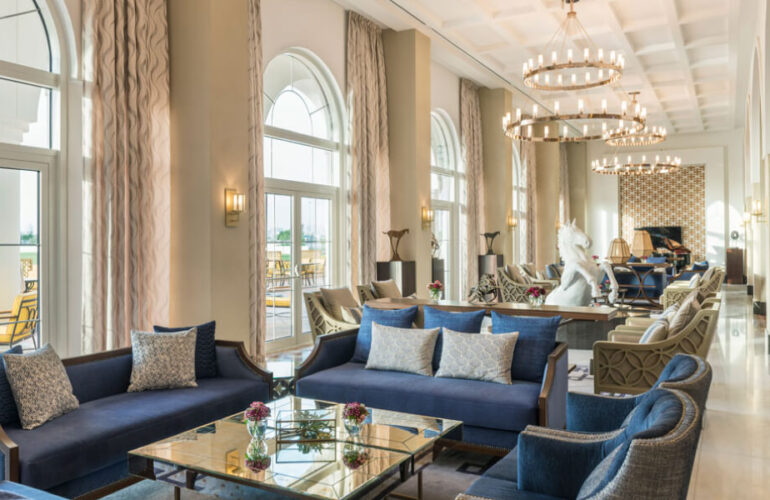 A grand hotel lounge with high ceilings, elegant furniture, and large arched windows at Al Habtoor Polo Resort & Club Dubai.