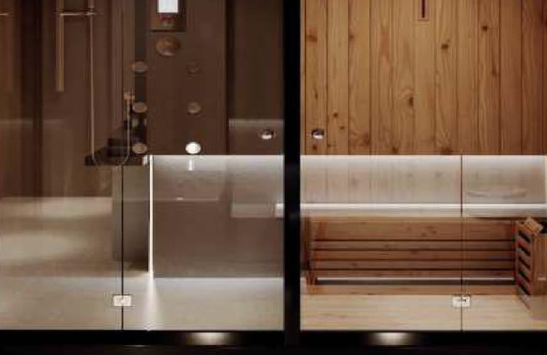 A sauna with white chairs and wooden walls and floor and a glass door