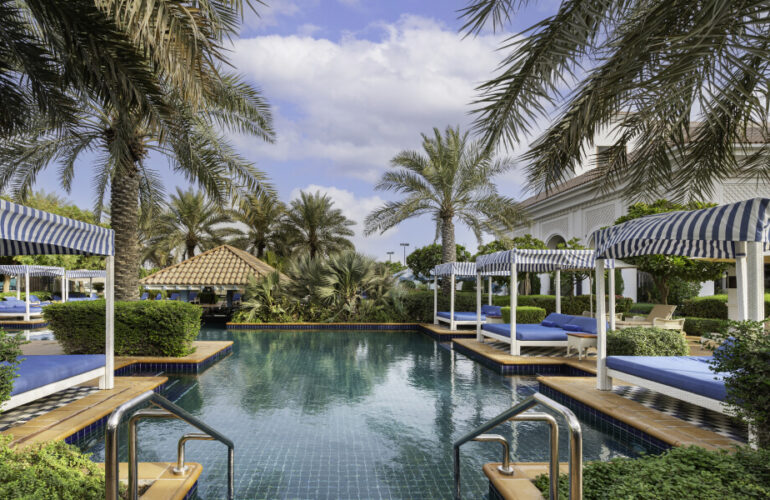 A stunning infinity pool surrounded by palm trees and luxurious cabanas at Al Habtoor Polo Resort & Club Dubai.