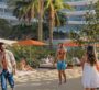 People enjoying a walk along Oystra’s luxury beachfront lined with palm trees and amenities.