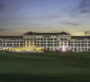 A luxurious hotel building at dusk with elegant lighting, part of Al Habtoor Polo Resort & Club Dubai.