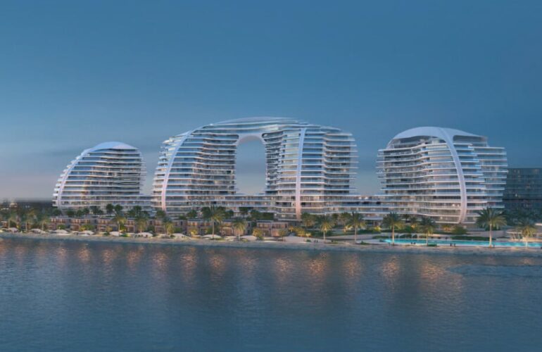 Night view of futuristic waterfront Oystra towers designed by Zaha Hadid, lit up against the water.