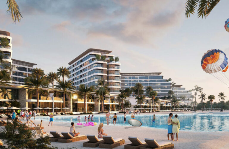 A small beach in the Pierside Marina Residences project where children are swimming, with a large building across from them.