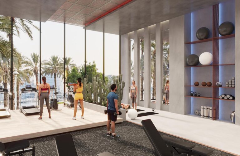 The gym at SAMANA Ocean Pearl 2 in Dubai, with large windows offering a view of the jacuzzi and pool, where people are working out facing the view.