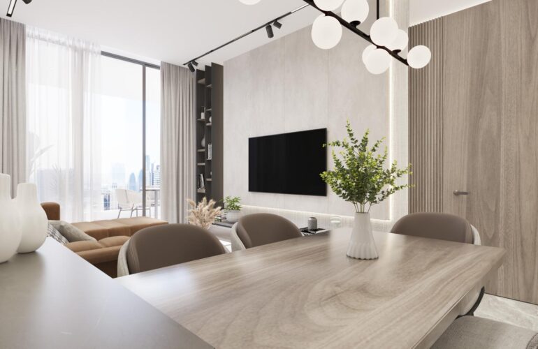 The reception hall at SAMANA Ocean Pearl 2 in Dubai, with a large table placed in the center and sofas arranged facing the TV. A lamp similar to a desk lamp sits on the table