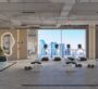 The gym at SAMANA Park Meadows in Dubai, with large windows and an outside view. Treadmills are placed by the windows, and yoga mats are in other areas