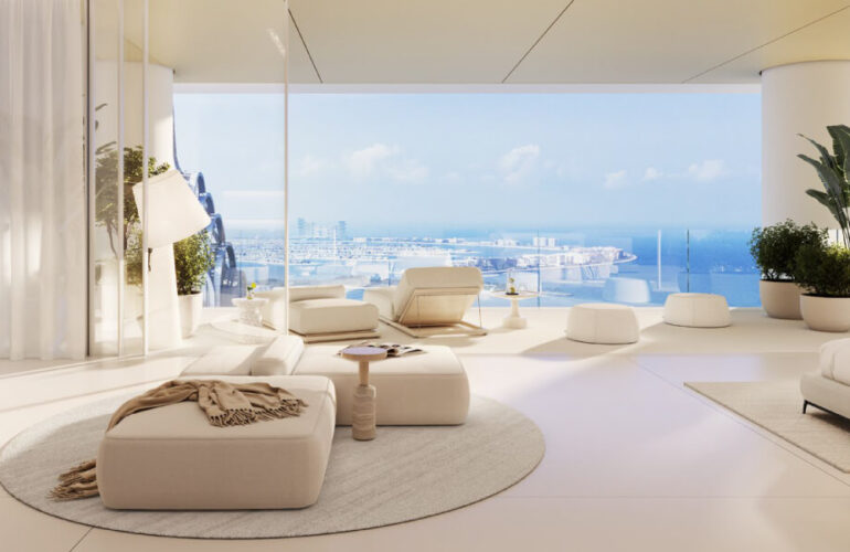 A view from inside the bedroom at The Chedi Private Residences in Dubai, with white walls and beautifully arranged white sofas. In the corner of the room, there is also a bed. Large windows behind the sofas offer a view of the outside, where the weather is clear and sunny.