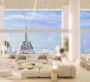 A view from inside the living room at The Chedi Private Residences in Dubai, with white sofas arranged facing the television. Behind the sofas, there is a large window offering a view of the outside, where the weather is sunny and clear