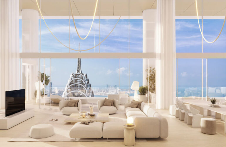 A view from inside the living room at The Chedi Private Residences in Dubai, with white sofas arranged facing the television. Behind the sofas, there is a large window offering a view of the outside, where the weather is sunny and clear