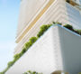 A view of The Chedi Private Residences in Dubai taken from below. Plants are visible at the base of the apartment, and the building extends upwards. The weather is sunny