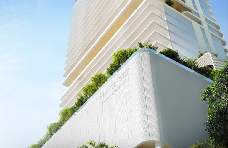 A view of The Chedi Private Residences in Dubai taken from below. Plants are visible at the base of the apartment, and the building extends upwards. The weather is sunny