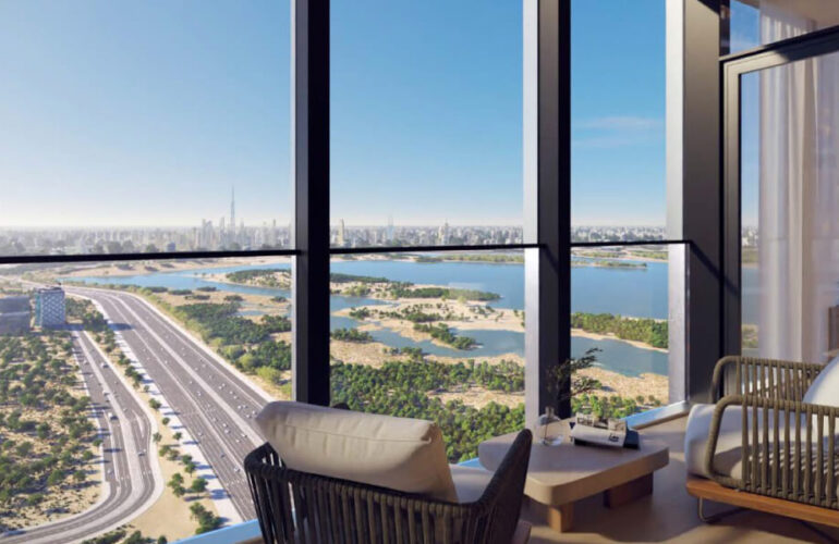 A room at The Element at Sobha One Apartments in Dubai, with two white sofas arranged facing a large window, offering a view of the sea and beach. The weather is sunny.