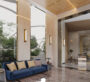 The reception area at Trinity - Reception in Dubai, with sofas and a large window behind them offering a view of the garden. The floor is ceramic, with a hallway. Part of Dubai’s luxury real estate.