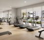 A gym where treadmills are arranged facing large windows