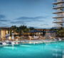 Large infinity pool surrounded by sun loungers and greenery at Lyvia by Palace